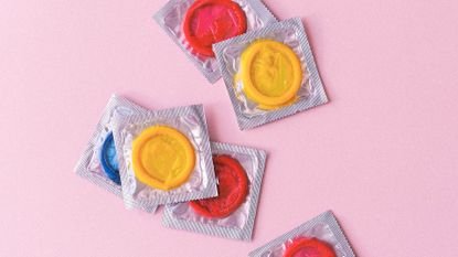 Condoms in packets on a pink background