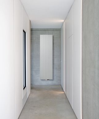 Narrow hallway with slim vertical radiator at one end and white wall panelling