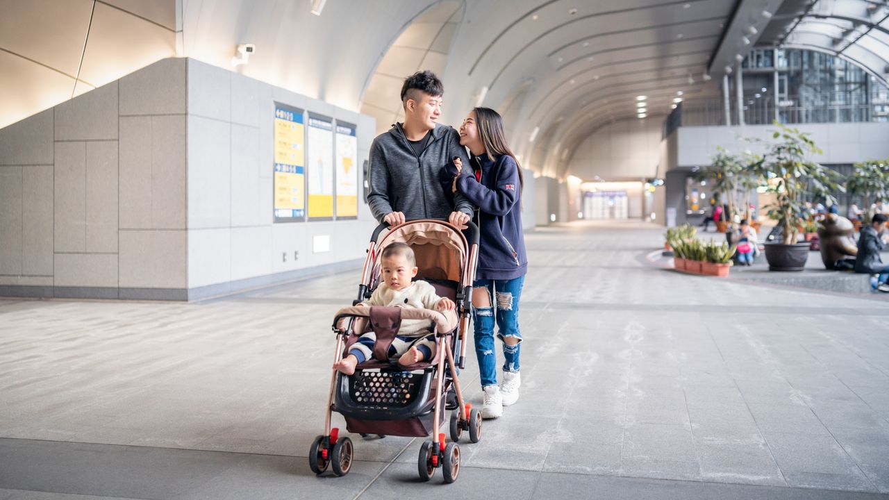 A family walking through an airport terminal with one of the best travel strollers