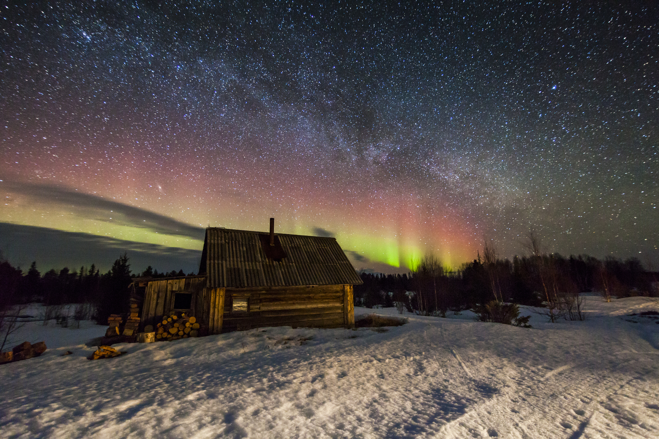 Auroras can be seen over a cabin in the Arctic during polar twilight.