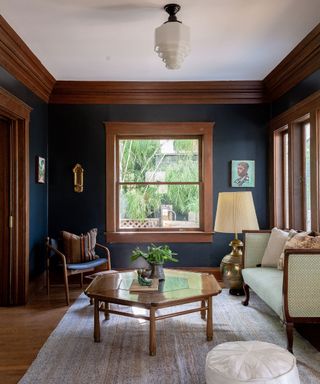 Small living room with dark wood paneling, dark blue painted walls, antique funiture, rug