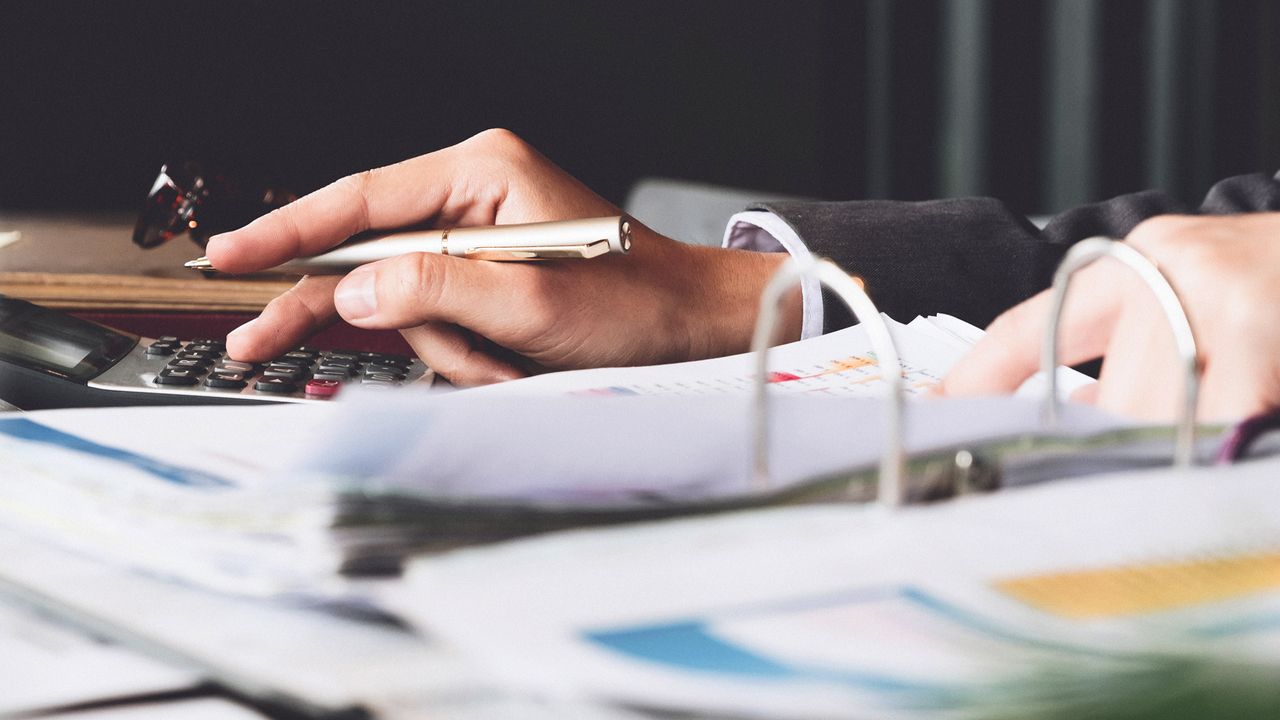 Person using a calculator to calculate the numbers for financial document