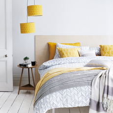 bedroom with white wall and yellow and white cushions on bed