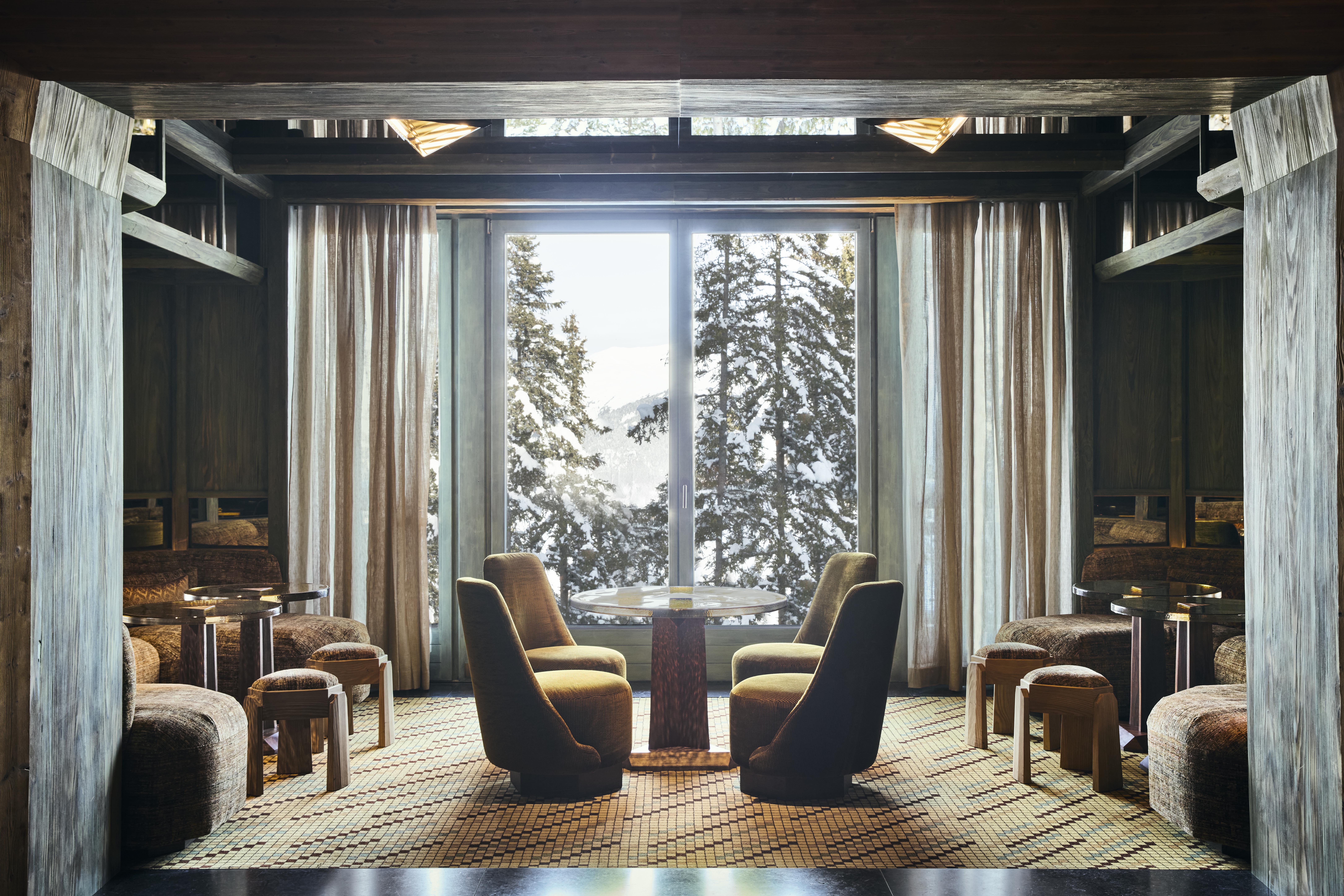 The elaborate, theatrical interiors of a ski chalet with wood wall paneling, plush textiles in different patternes, colors, and textures, plenty of paintings and sculptures adorning its halls, and a dimly lit atmosphere.