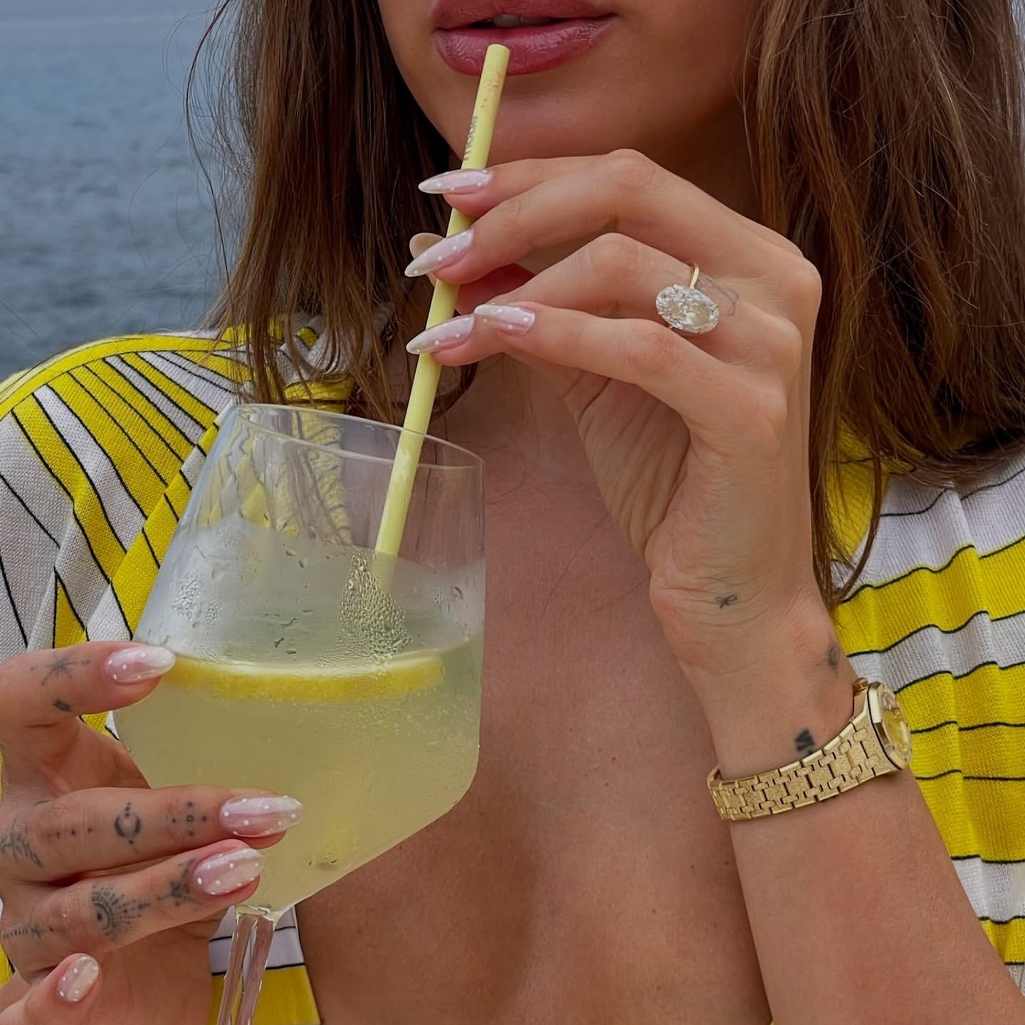 Hailey Bieber shows off her polka dot chrome manicure while sipping a lemon martini.