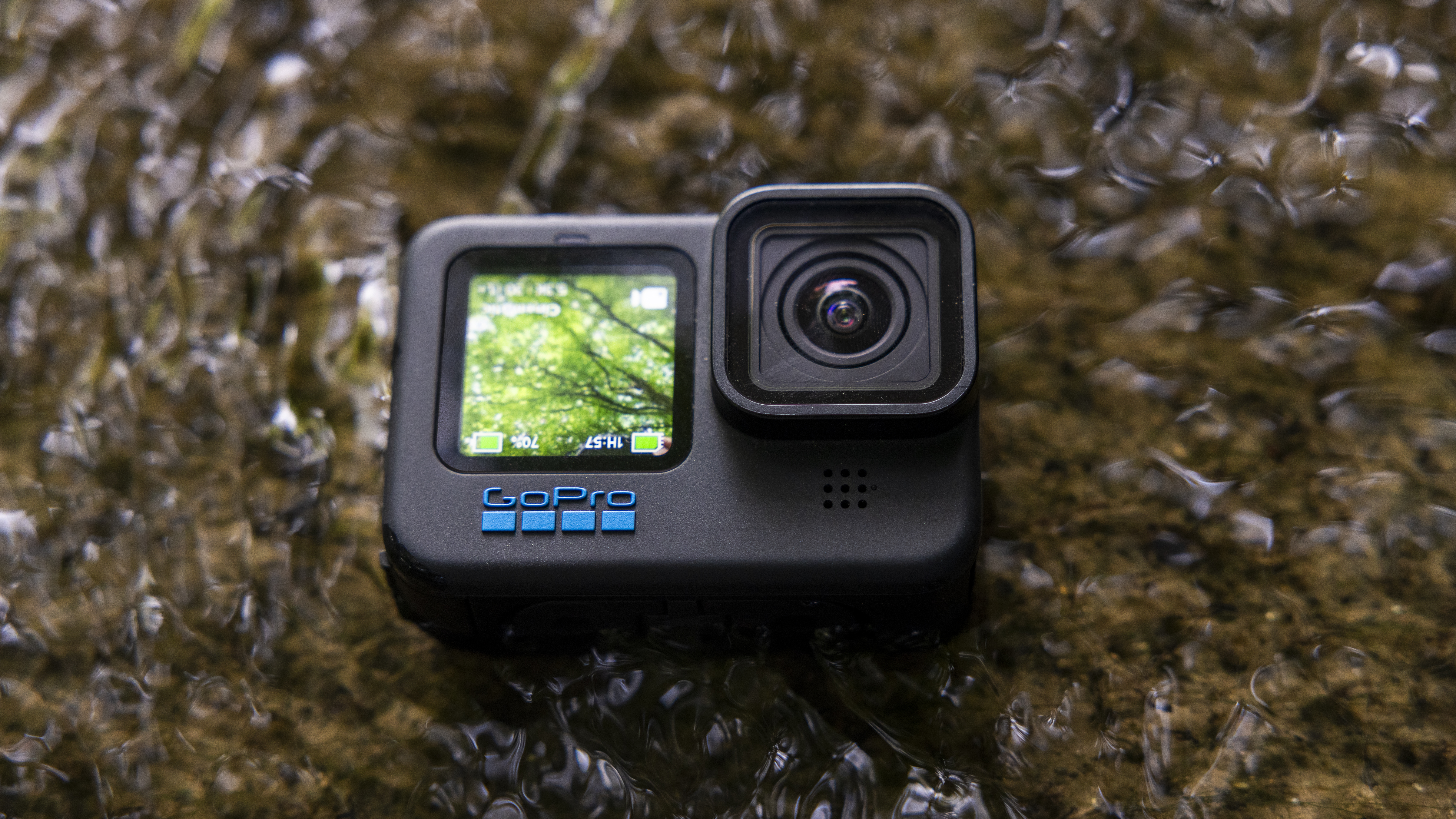 A GoPro Hero 12 Black submerged in a stream with the front screen on