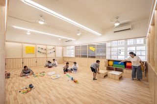 A teacher and children in spacious classroom