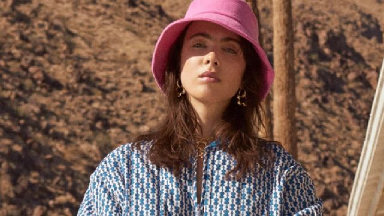 A woman in a pink bucket hat and blue patterned jacket