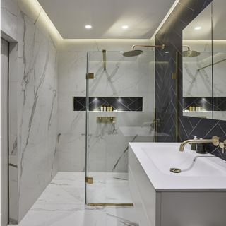 walk in shower with white basin, white and grey tiles and black tiles