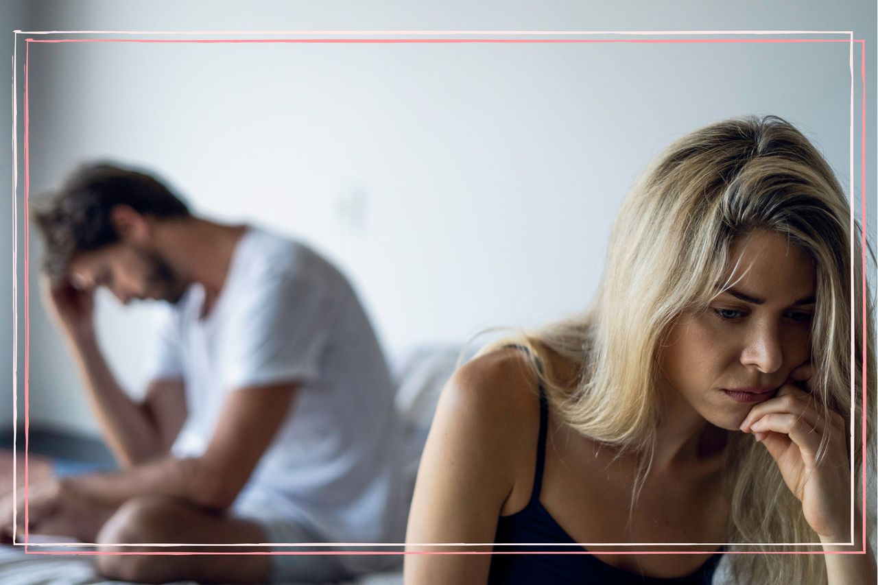 An unhappy couple sat in a bedroom facing away from each other