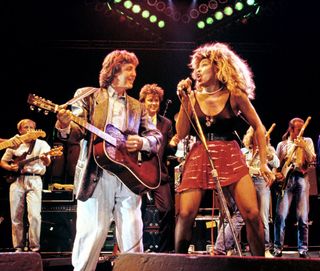 Paul McCartney and Tina Turner performing on stage at The Prince's Trust 10th Birthday Party at Wembley Arena, London, United Kingdom on 20th June 1986. Behind them from left to right are: Mark King, Paul Young, Rick Parfitt and Francis Rossi.