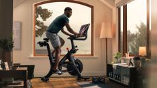 Best Peloton alternatives: pictured here, an athletic man riding a Peloton bike in a living room