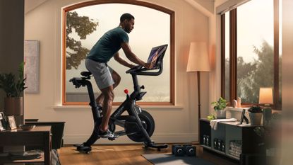 Best Peloton alternatives: pictured here, an athletic man riding a Peloton bike in a living room