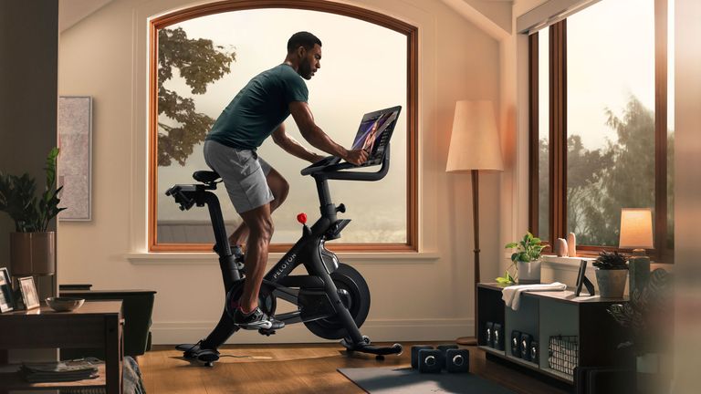 Athletic man riding a Peloton bike in a living room