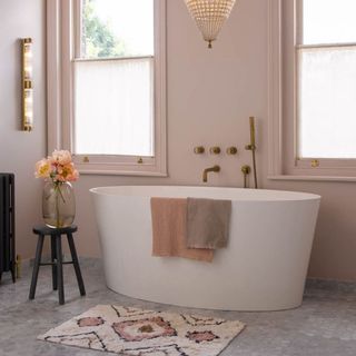 White bath with towel in neutral bathroom of grey stone effect floor