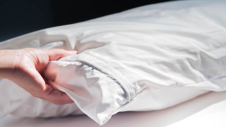 a woman placing a pillow onto the bed