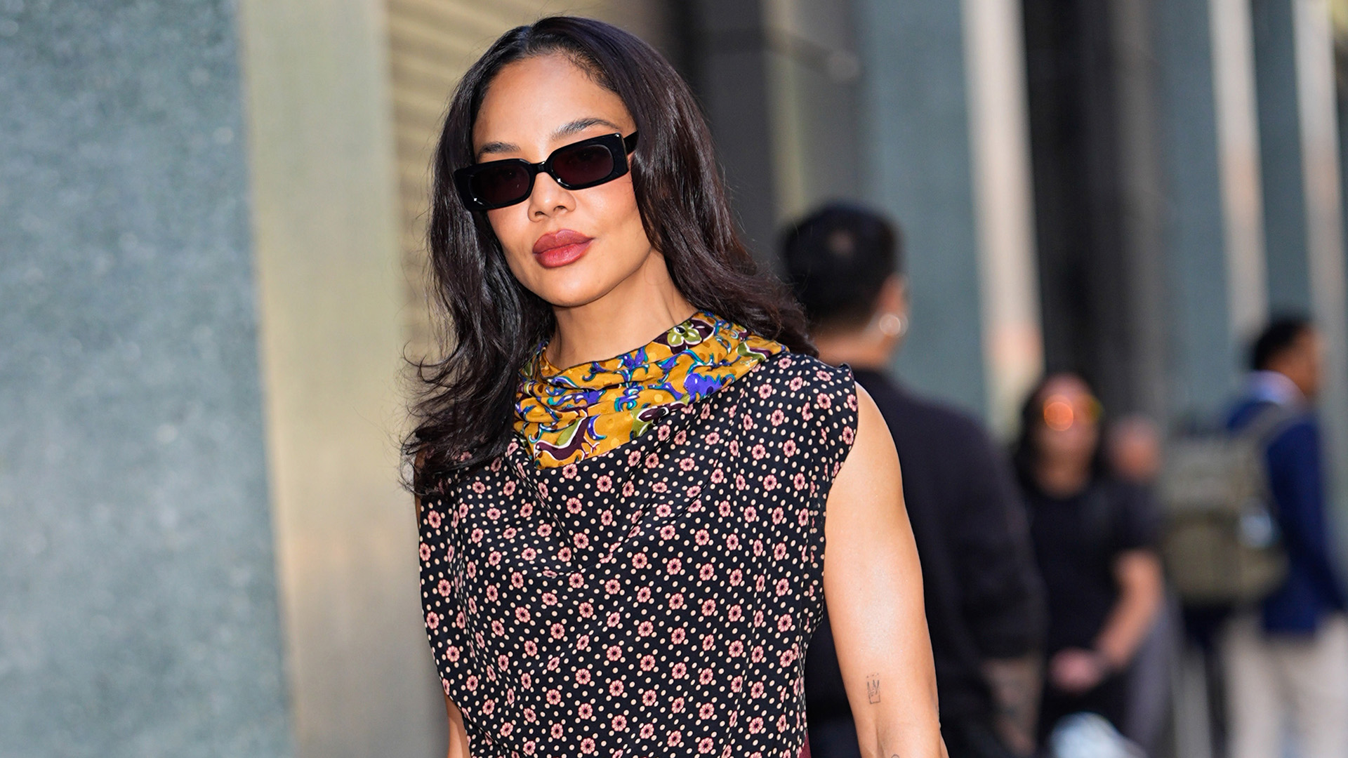 Tessa Thompson wearing a scarf-print dress with a cream satin handbag and cream leather pumps