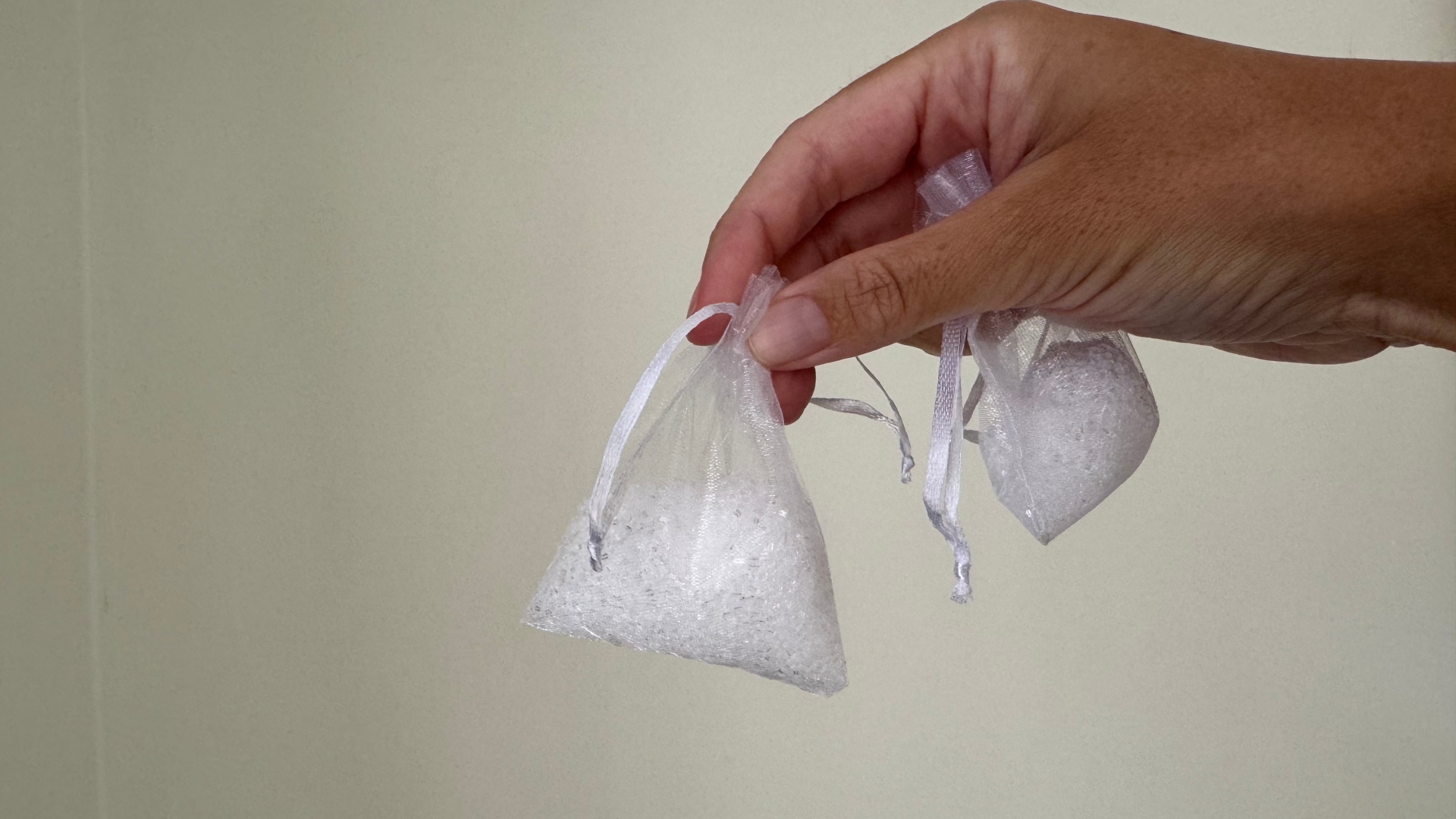 A hand holds two bags of epsom salt and essential oils for a spider repelling hack