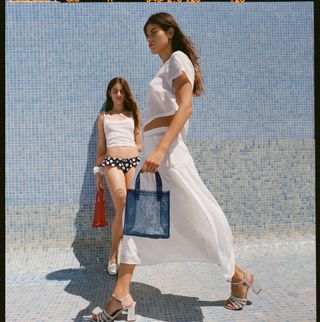 two women wear white skirts and t shirts from the maryam nassir zadeh collaboration in front of a tiled wall