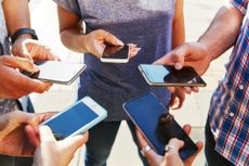 A bunch of people standing in a circle holding out their smartphones