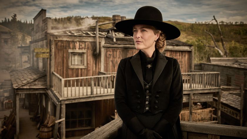 Gillian Anderson as Constance Van Ness wearing a black hat and outfit. She&#039;s looking at something off camera with a Western background behind her.