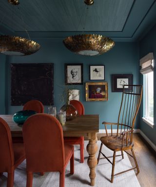 a blue dining room with wood and rust color chairs