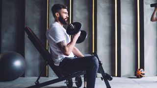 A man performing incline bicep curl in gym