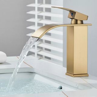 A brushed brass waterfall tap with flowing water