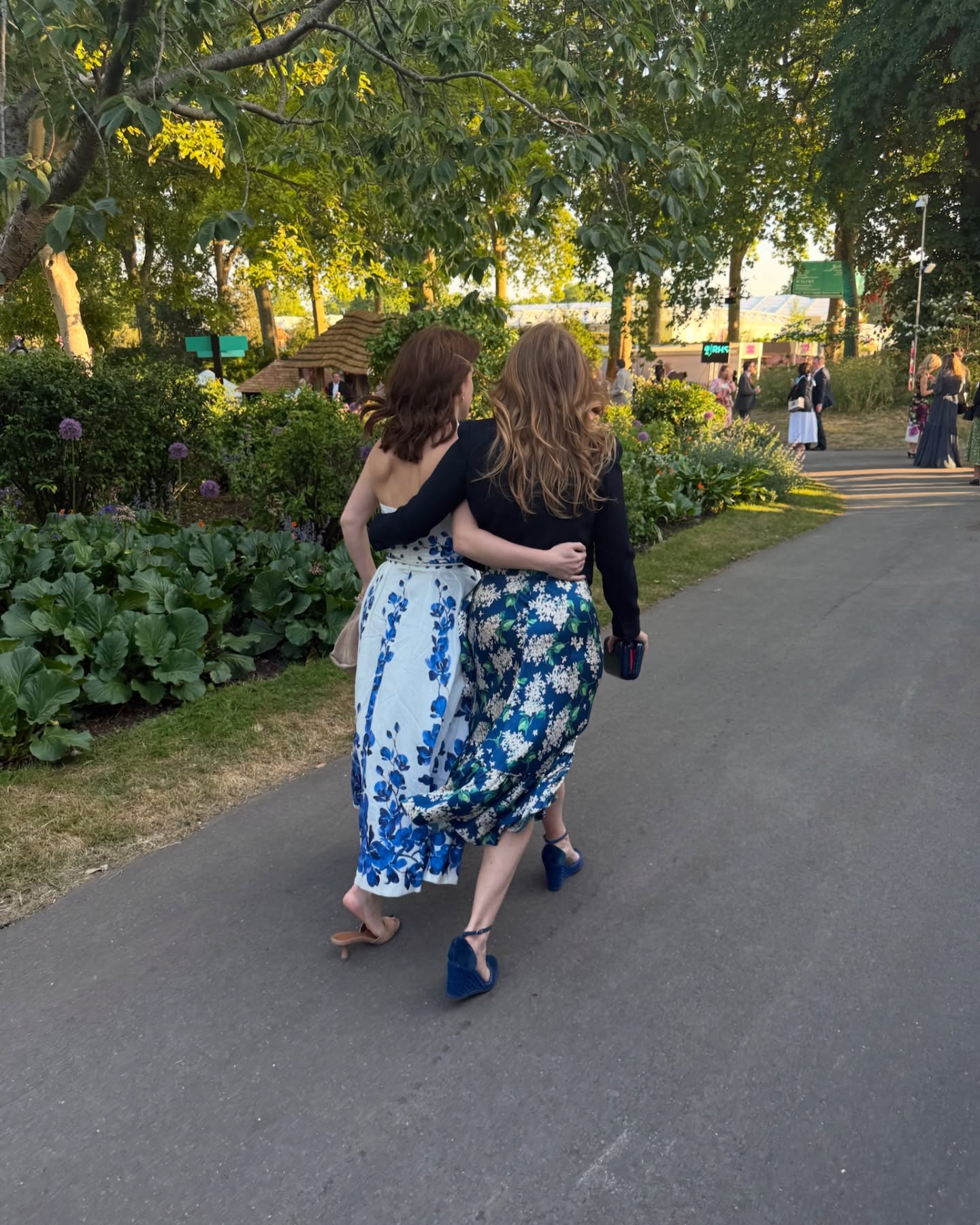 Princess Eugenie walking with her arm around Princess Beatrice at the Chelsea Garden Party