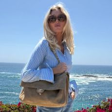 Model Elsa Hosk wears a blue button down shirt with blue jeans, boat shoes and a Chanel tote bag.