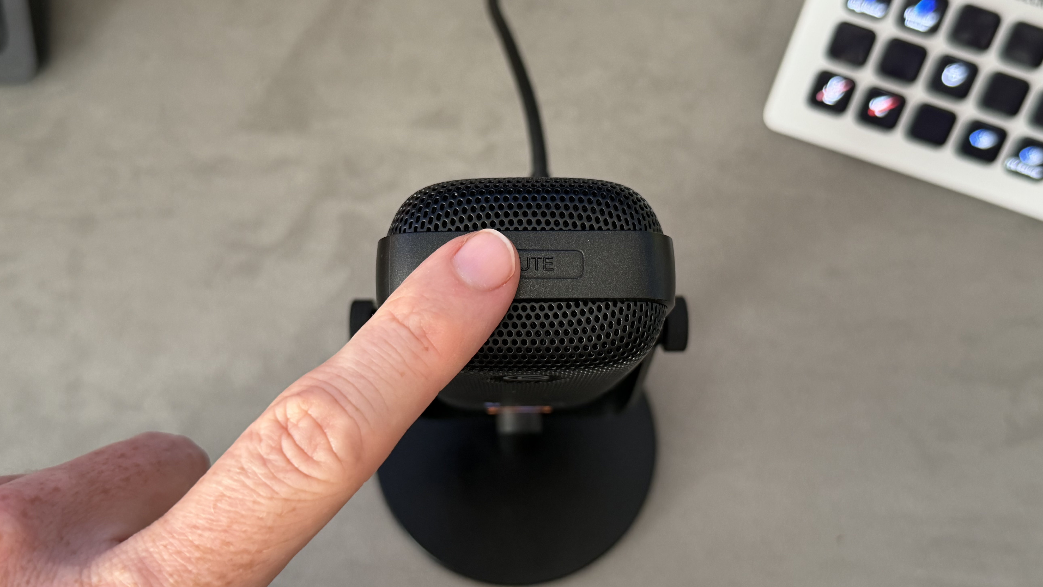 A reviewer touching the capacitive mute button on the top of the Elgato Wave 3 Mk2