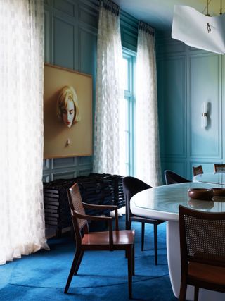Dining room with ombre yellow-green and aqua walls, cobalt carpet and wood chairs and table
