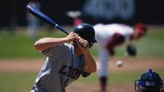 Baseball player preparing to strike ball, pitcher in background