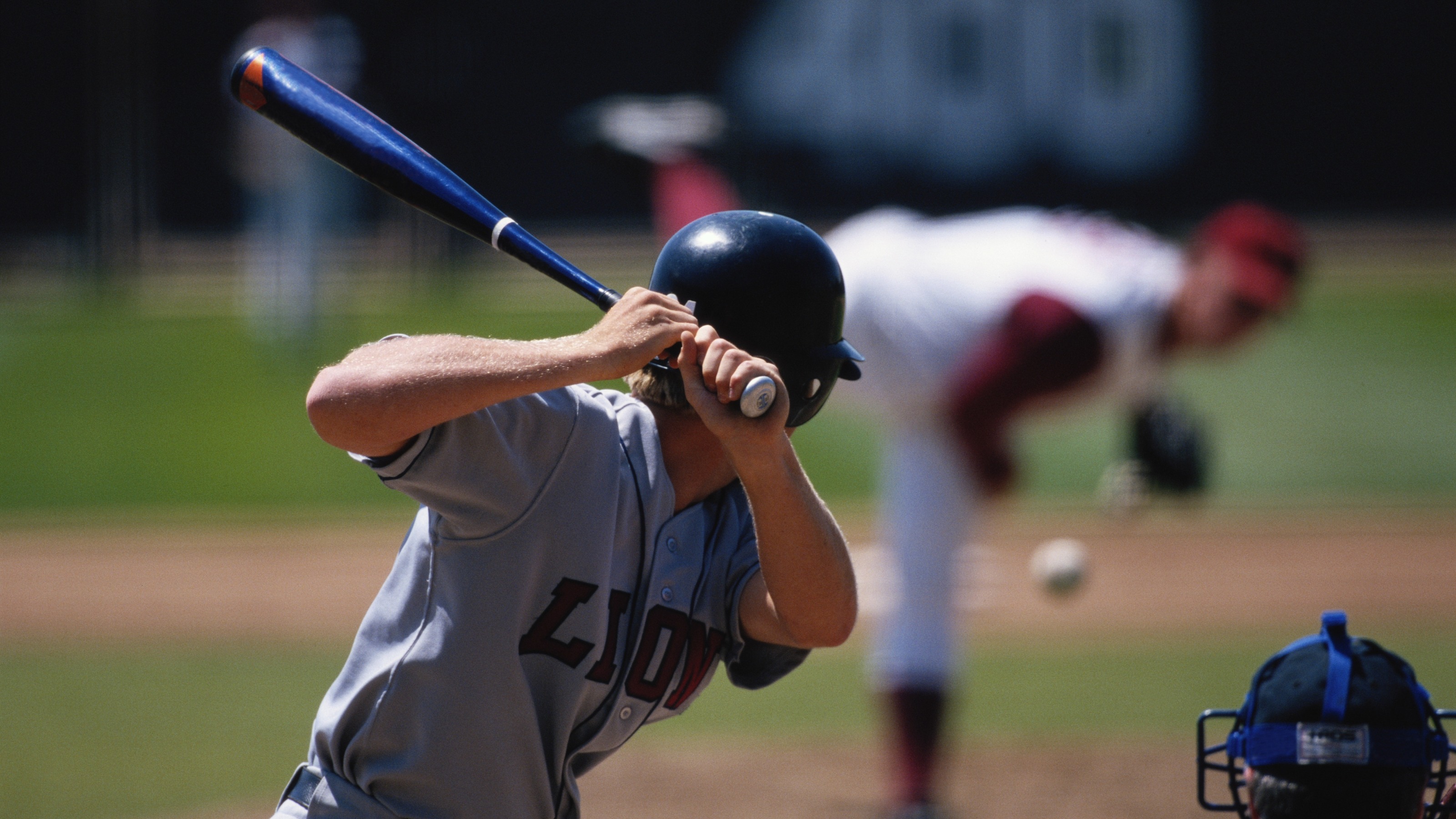 Baseball player preparing to strike ball, pitcher in background