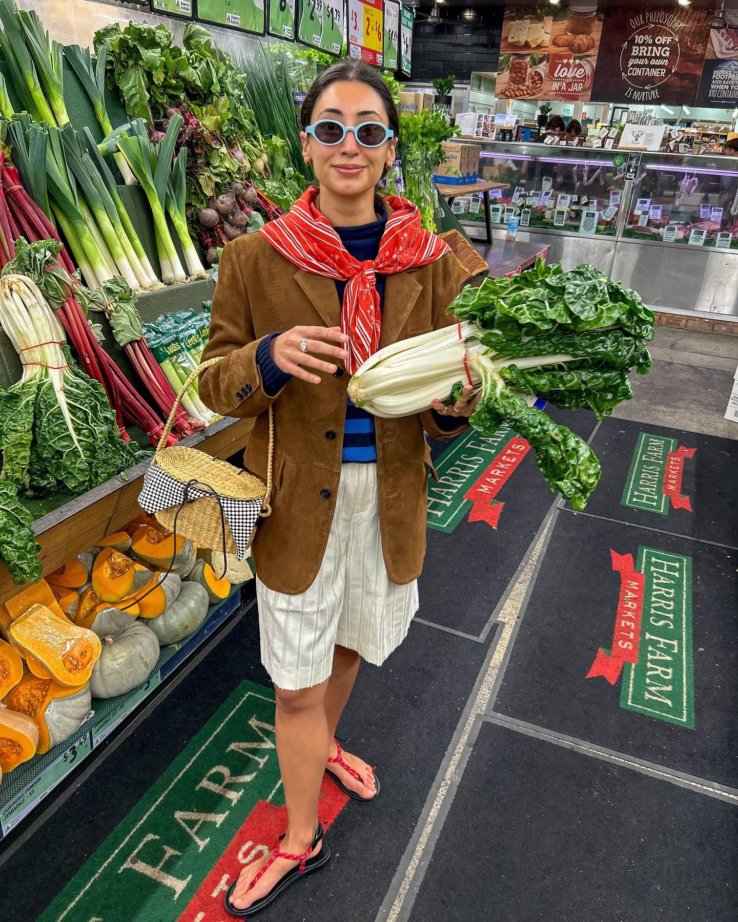 Influencer Barbra wears linen shorts, stripped jumper a brown blazer and holds a wicker bag.