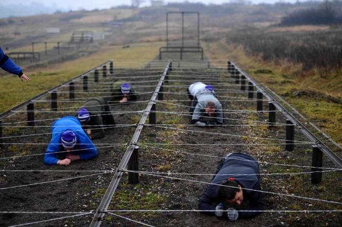 Heads down! Members of the Omega Pharma-QuickStep team crawl their way though an obstacle course