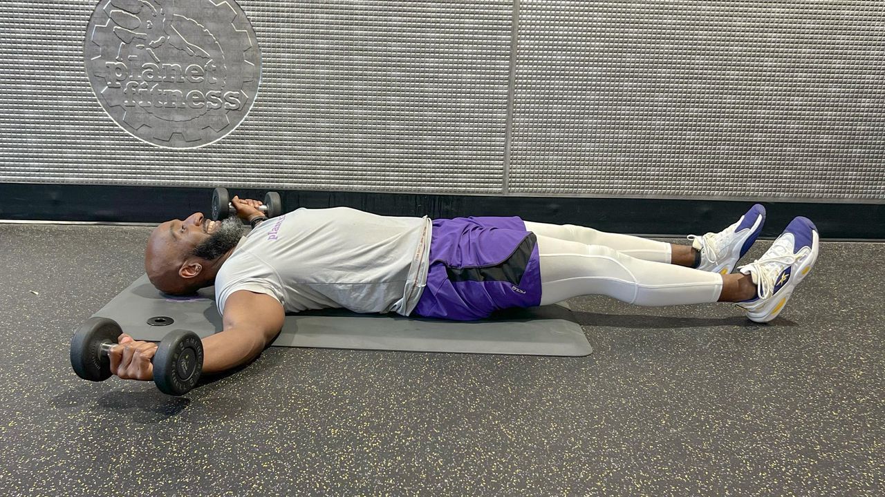 Teddy Savage starting a dumbbell floor chest fly to alternating knee tuck