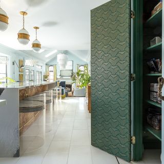 Green geo print wallpapered closet in large open plan kitchen
