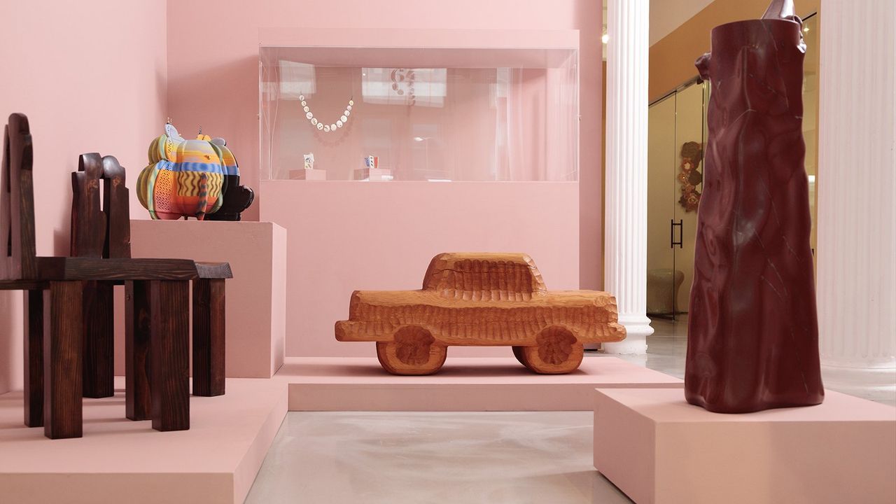 A whimsical gallery installation features cartoon-like cars, chairs, pearl necklaces and more.