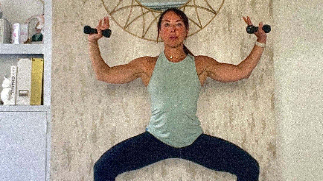 Lucy Miller performing a plie with shoulder press at home