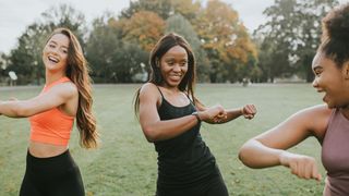 A group of three women exercise together in a park