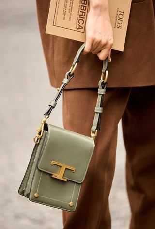 a close-up photo of a woman carrying a green crossbody phone bag