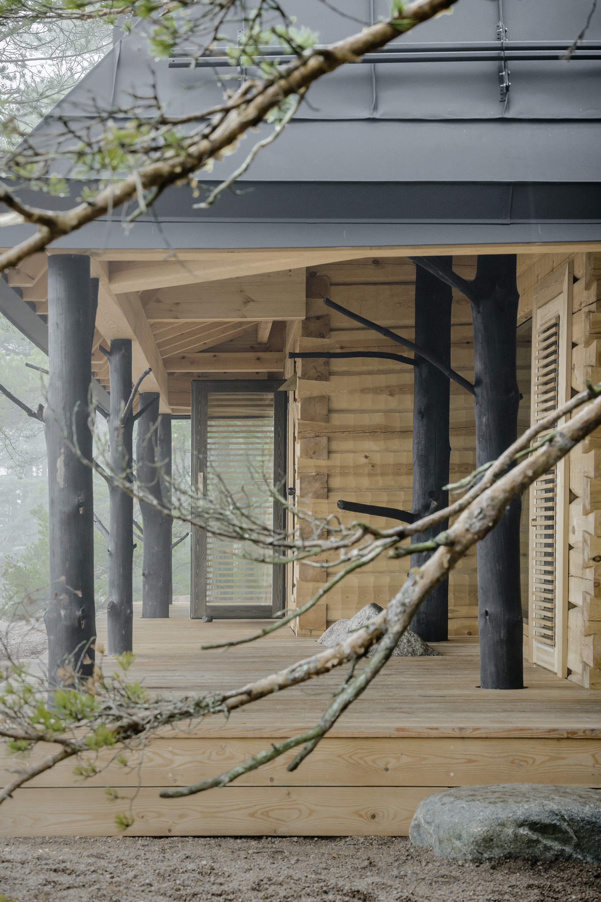 Puusauna, a wooden sauna building using entire tree trunks for columns, designed by Jaakko Torvinen and immersed in a forest