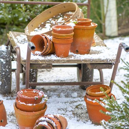 Terracotta plant pots and sifter on cart in the snow