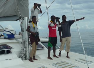 This wildlife conservation survey team in Tanzania tracks a group of false killer whales from the deck of their survey boat.