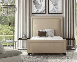Saatva latex hybrid mattress on a bed in a large bedroom with artwork above the bed, matching bedside tables and tall windows in a classic style bedroom