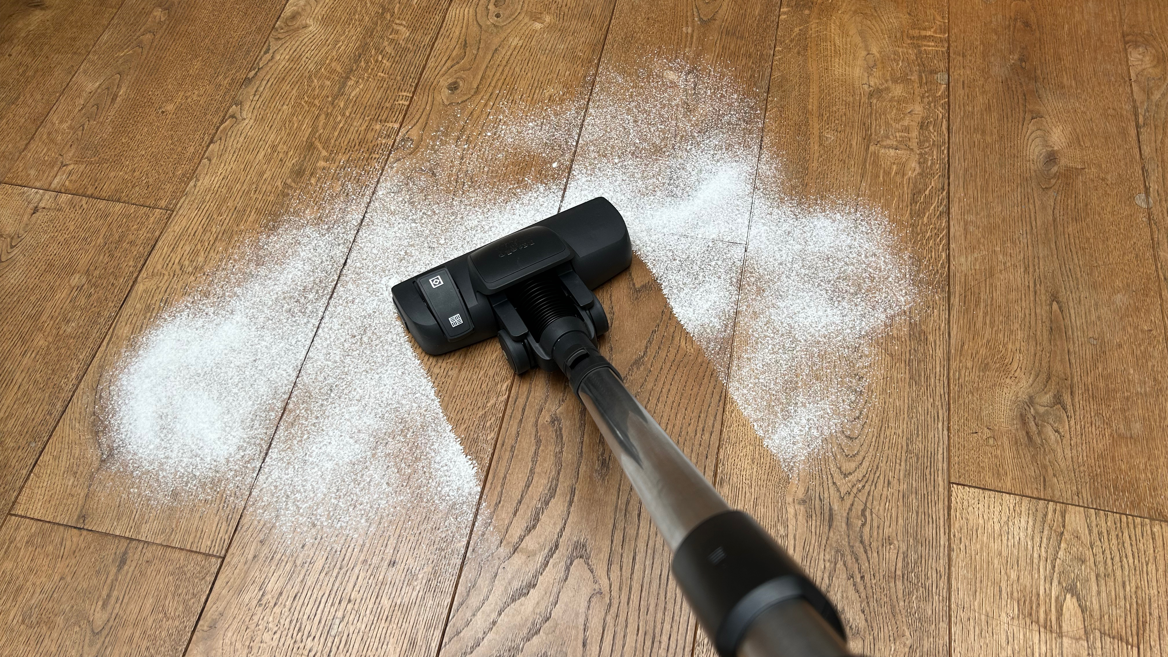 Miele Blizzard CX1 canister vacuum cleaning flour from a wooden floor