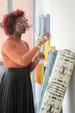 A portrait of Chrissa Amuah looking at the textiles.