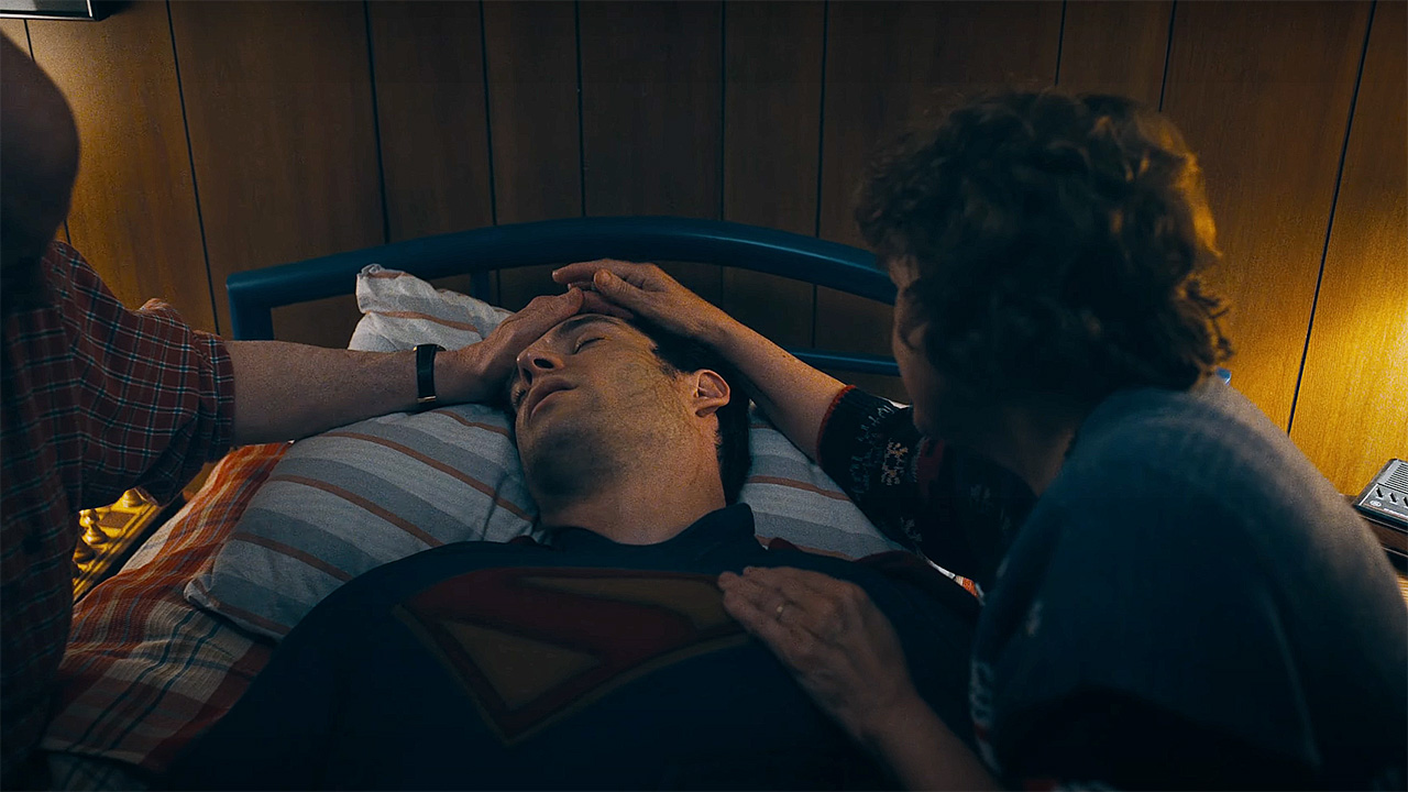 An injured Clark Kent lying on his bed surrounded by his adoptive parents in 2025's Superman movie