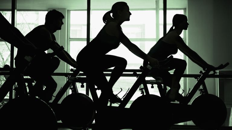 Silhouettes of people on bikes in spin class